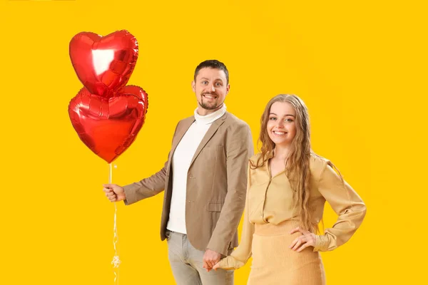 Happy Young Couple Heart Shaped Balloons Yellow Background Valentine Day — Fotografia de Stock