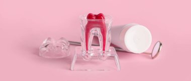 Plastic tooth with paste and dental mirror on pink background