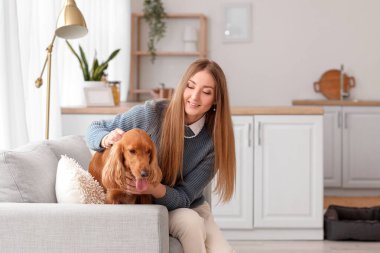 Young woman with red cocker spaniel sitting on sofa in kitchen