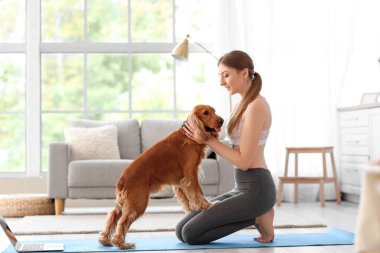 Sporty young woman with red cocker spaniel at home