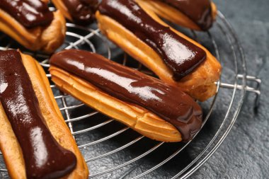 Grid with tasty chocolate eclairs on dark color background