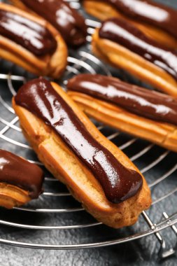 Grid with tasty chocolate eclairs on dark color background