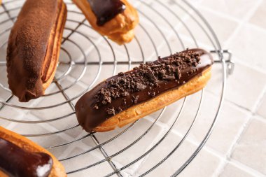 Grid of tasty chocolate eclairs on light tile, closeup