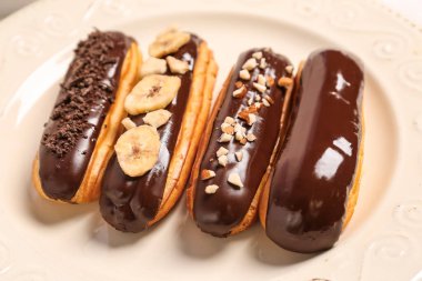 Plate of delicious chocolate eclairs, closeup