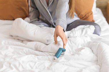 Sick woman with inhaler in bedroom