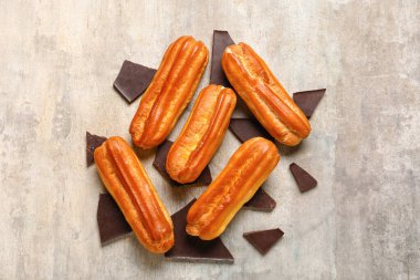 Composition with sweet eclairs and chocolate pieces on grunge background