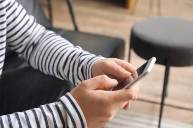 Young man using mobile phone in office, closeup