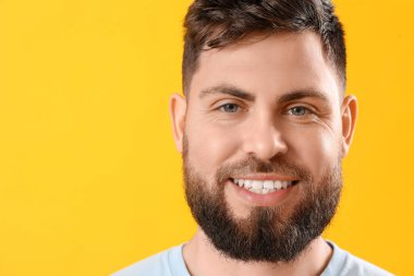 Young man with beautiful smile on yellow background, closeup