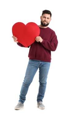 Young bearded man with big paper heart for Valentine's Day on white background