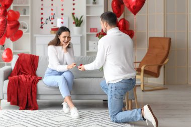 Young man proposing to his beloved girlfriend at home on Valentine's Day
