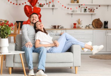 Happy couple sitting in kitchen on Valentine's Day
