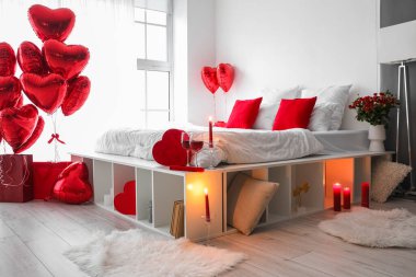 Interior of bedroom decorated for Valentine's Day with balloons, candles and gifts