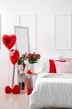 Interior of light bedroom decorated for Valentine's Day with balloons, flowers and gifts