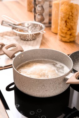 Cooking pot with boiling pasta on electric stove in kitchen