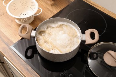 Cooking pot with boiling pasta on electric stove in kitchen