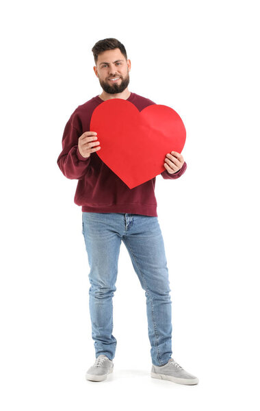 Молодой бородатый человек с большим бумажным сердцем на День Святого Валентина на белом фоне