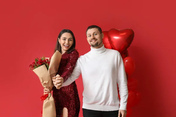 Happy couple in love with roses on red background. Valentine\'s Day celebration