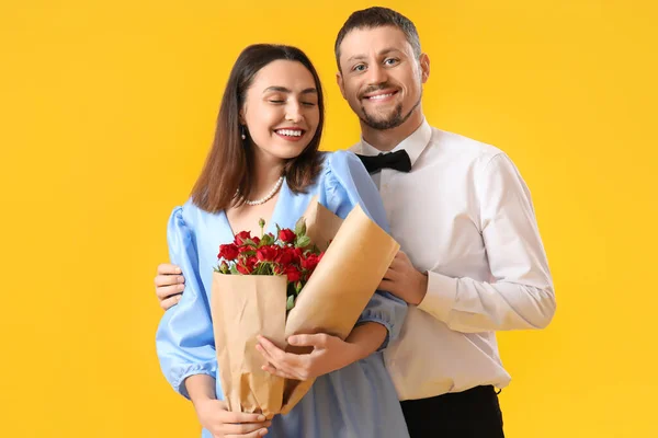Happy couple in love with roses on yellow background. Valentine\'s Day celebration