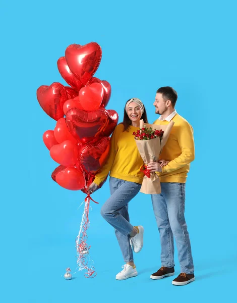 Happy couple in love with roses and balloons on blue background. Valentine\'s Day celebration