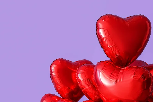 Heart-shaped balloons for Valentine\'s Day near lilac wall, closeup