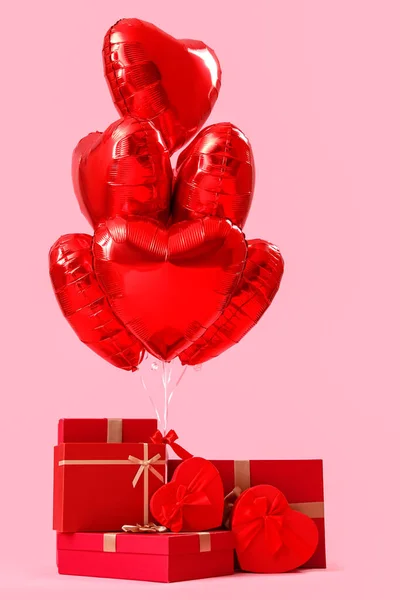 Gifts with heart-shaped balloons for Valentine\'s Day on pink background