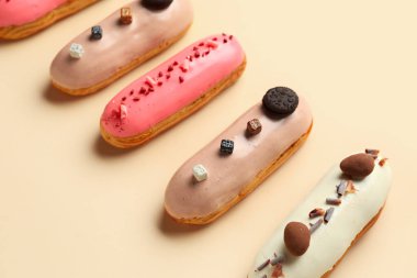 Various glazed eclairs on beige background