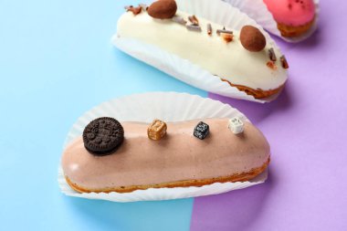 Various glazed eclairs on blue and lilac background