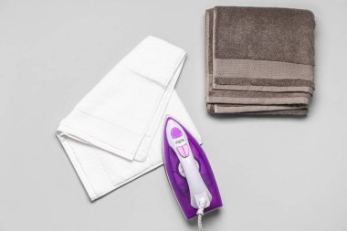 Açık gri arkaplanda elektrikli demir ve pamuk havlular