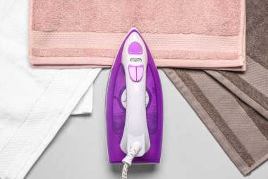 Açık gri arkaplanda elektrikli demir ve pamuk havlular