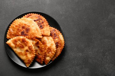 Plate with tasty chebureks on dark grunge background