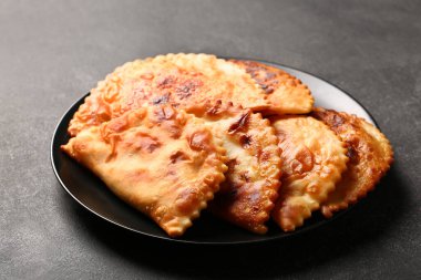 Plate with tasty chebureks on dark grunge background