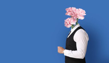 Young businessman with bouquet of flowers instead of his head on blue background with space for text