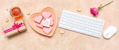 Composition with tasty heart shaped cookies, gift, cup of tea and computer keyboard on grunge background. Valentine's Day celebration