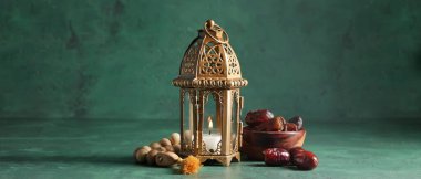 Muslim lamp and tasbih with dates on green background