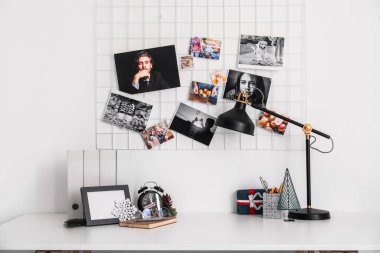 Workplace with Christmas gift and alarm clock near light wall