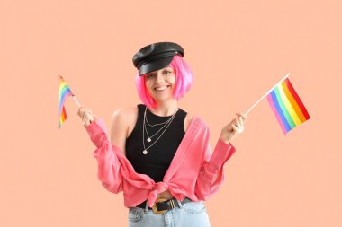 Beautiful young woman with LGBT flags on pink background