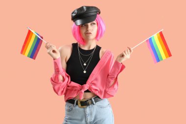 Beautiful young woman with LGBT flags on pink background
