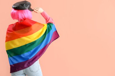 Young woman with LGBT flag on pink background, back view