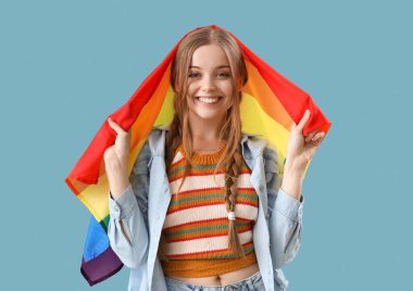 Beautiful young woman with LGBT flag on blue background