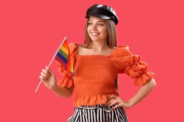 Beautiful young woman in hat with LGBT flag on red background