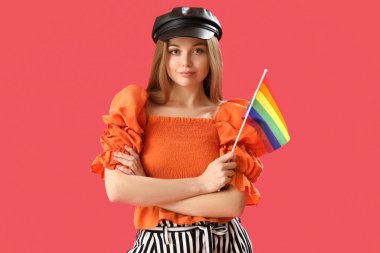 Beautiful young woman in hat with LGBT flag on red background