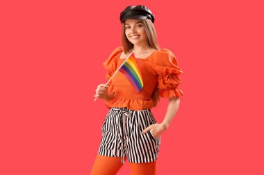Beautiful young woman in hat with LGBT flag on red background