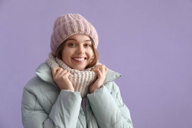 Leylak arka planında kışlık giysiler içinde donmuş genç bir kadın.