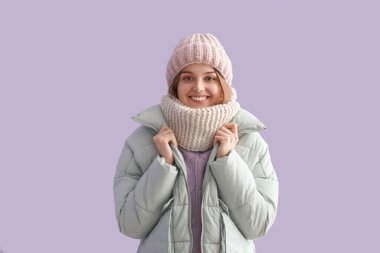 Leylak arka planında kışlık giysiler içinde donmuş genç bir kadın.