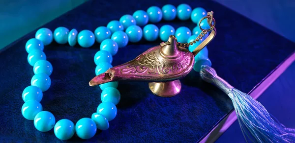 Aladdin lamp of wishes, tasbih and Koran on blue background