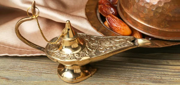 Aladdin lamp of wishes and dates on wooden table, closeup