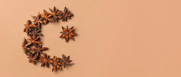 Crescent and star made of anise as symbol of Islam on brown background with space for text