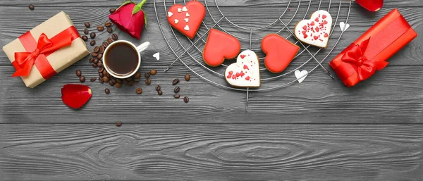Composition with tasty heart shaped cookies, gifts and cup of coffee on dark wooden background with space for text. Valentine\'s Day celebration