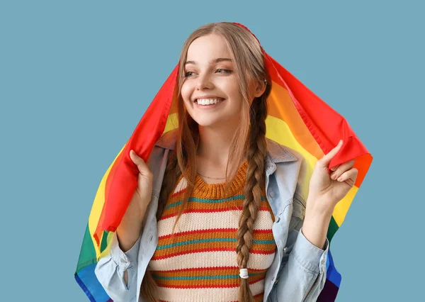 Beautiful young woman with LGBT flag on blue background
