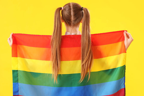 Красивая молодая женщина с флагом ЛГБТ на желтом фоне, вид сзади